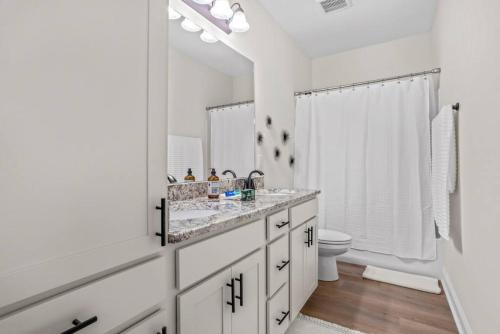 Baño blanco con lavabo y aseo en Four-bedroom house in Iowa, La, en Iowa
