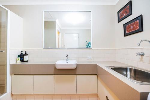 un baño con lavabo y espejo en Ocean Sunsets - 2 bedroom converted warehouse apartment, en Fremantle