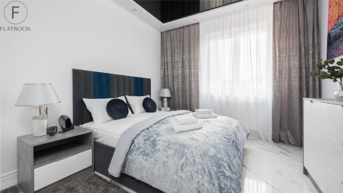 a white bedroom with a large bed and a window at Flatbook - City Center Apartments Monte Cassino in Sopot