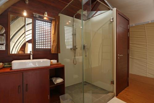 a bathroom with a glass shower and a sink at Floating Jungloo in Phnom Penh