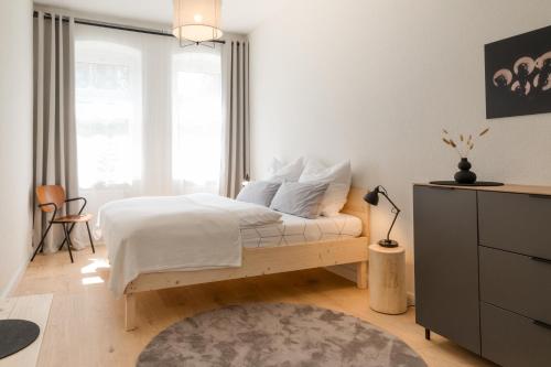 1 dormitorio con cama con sábanas blancas y alfombra en Ferienwohnung Kulturbeutel, en Erfurt