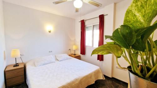 a bedroom with a white bed and a potted plant at AA Guest - Don Juan Eco Front Sea Views Apartment in Fuengirola