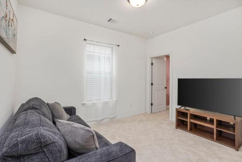 a living room with a couch and a flat screen tv at Brand-new home close to LSU campus in Baton Rouge