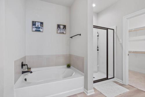 a white bathroom with a tub and a shower at Brand-new home close to LSU campus in Baton Rouge