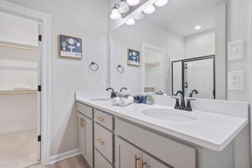 a white bathroom with a sink and a mirror at Brand-new home close to LSU campus in Baton Rouge