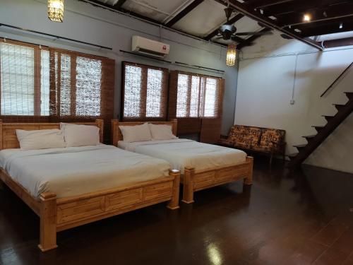 two beds in a room with a staircase and windows at Mori Jonker in Malacca
