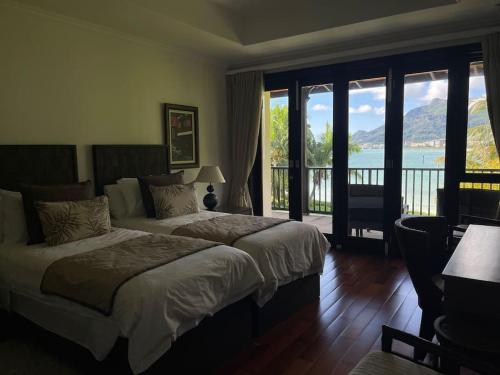 a bedroom with two beds and a view of the water at Paradise Villa Eden Island in Mahe