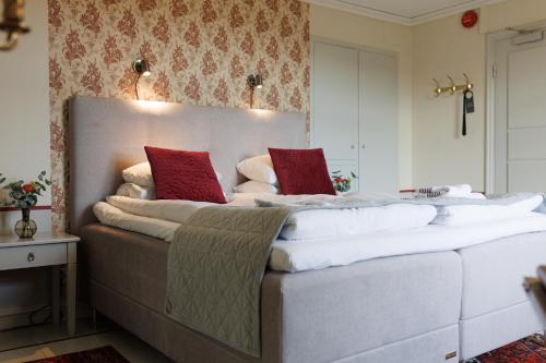 a bedroom with a large bed with red pillows on it at Munkedals Herrgård in Munkedal