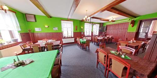 een restaurant met groene muren en houten tafels en stoelen bij motorest U KONĚ in Stein Schönau