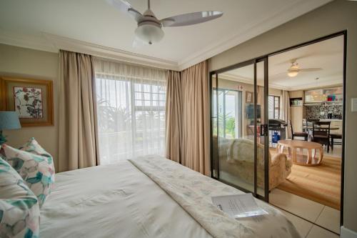 a bedroom with a bed and a living room at On the Beach Guesthouse Jeffreys Bay in Jeffreys Bay