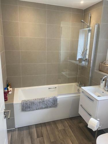 een badkamer met een bad en een wastafel bij Very large double room with corner sofa and Sky TV in Newhaven