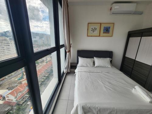 a bedroom with a bed and large windows at Urban Suites - Penang in Jelutong
