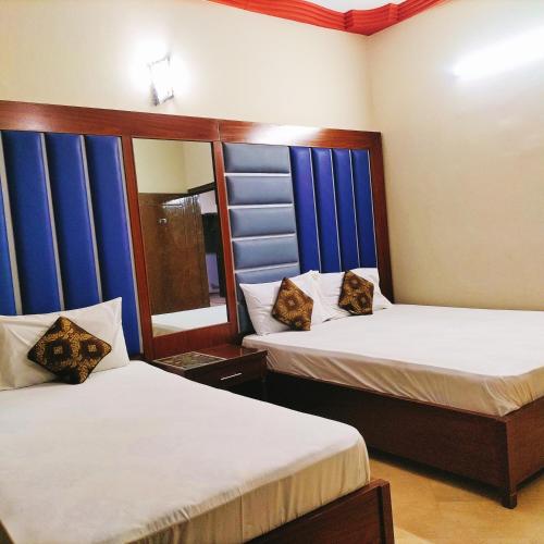 two beds in a room with blue windows at GULSHAN PALACE Near AghaKhanHospital ExpoCenter Airport in Karachi