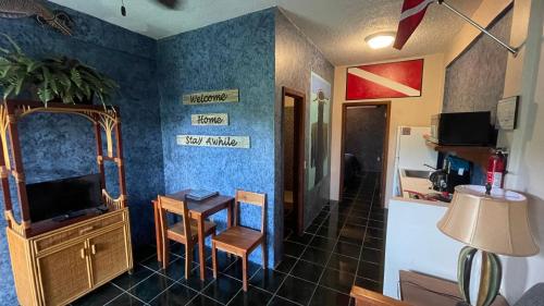 a living room with a television and a table with a desk at Belize Budget Suites in San Pedro