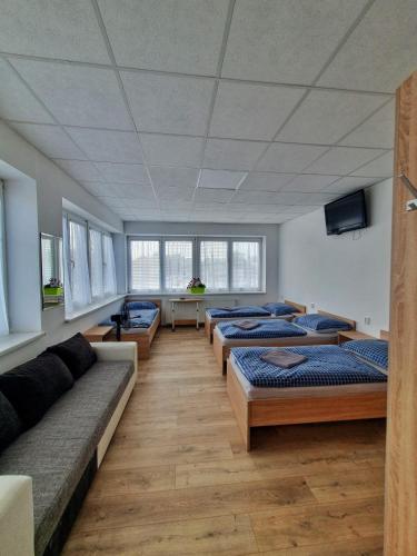 una habitación con una fila de camas y un sofá en UBYTOVŇA BYTČA, en Bytca