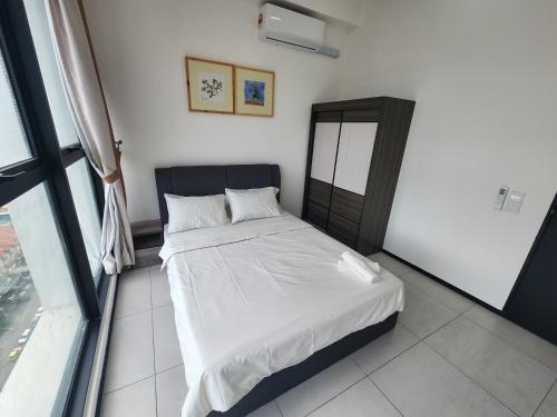 a bedroom with a bed with white sheets and a window at Urban Suite - George Town in Jelutong