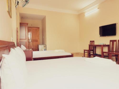 a hotel room with two beds and a flat screen tv at KHÁCH SẠN CÚC PHƯƠNG in Dĩ An