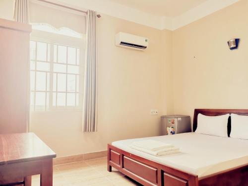 a white bedroom with a bed and a window at KHÁCH SẠN CÚC PHƯƠNG in Dĩ An