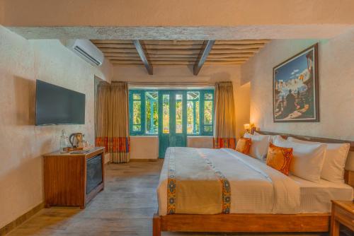 a bedroom with a large bed and a television at Tree of Life Birdsong Chalets , Dharamshala in Dharamshala