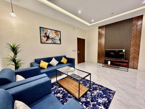 a living room with blue couches and a tv at شقة خاصة مؤثثة بالكامل للتأجير اليومي in Hafr Al Baten