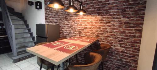 - une table et des chaises dans une pièce dotée d'un mur en briques dans l'établissement Chez Louis - Appartement Central, à Rethel