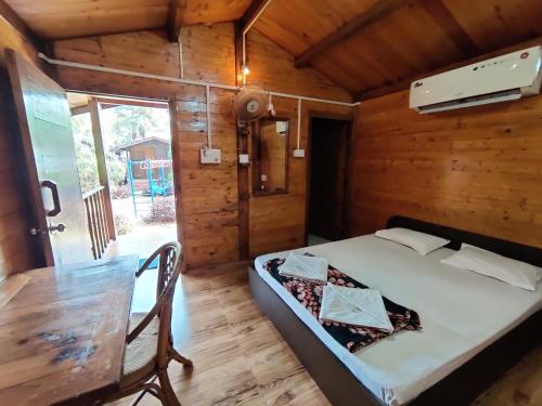 a bedroom in a wooden cabin with a bed and a table at Pousada Donaciana - Beach Cottages in Baga