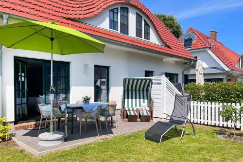 une terrasse avec une table, des chaises et un parasol dans l'établissement Sonneninsel, à Zingst