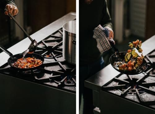 a person cooking food in a pan on a stove at The Amalfi in Hepburn Springs