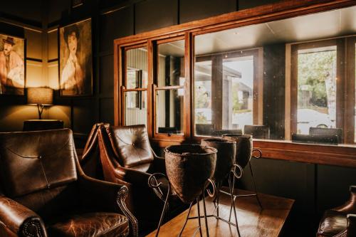 a room with leather chairs and a table and windows at The Amalfi in Hepburn Springs