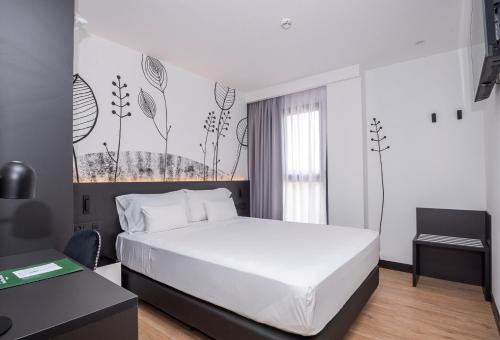 1 dormitorio con 1 cama blanca grande y escritorio en Sercotel Plana Suites, en Vall de Uxó