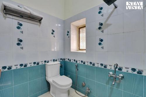a bathroom with a toilet and blue and white tiles at Jungle Retreat by VEO - Part of StayVista in Bāli