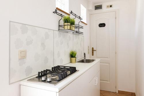 a white kitchen with a stove and a sink at Lexi Apartman private HydroMassage Hot Tub Balatonboglár in Balatonboglár