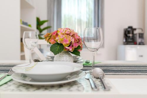 a table with a plate and a vase of flowers and glasses at Lexi Apartman private HydroMassage Hot Tub Balatonboglár in Balatonboglár