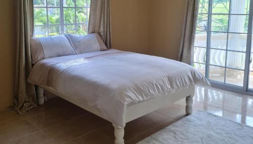 Cama blanca en habitación con ventana en Luxury 3-Bed House in St Ann's Ocho Rios, en Priory