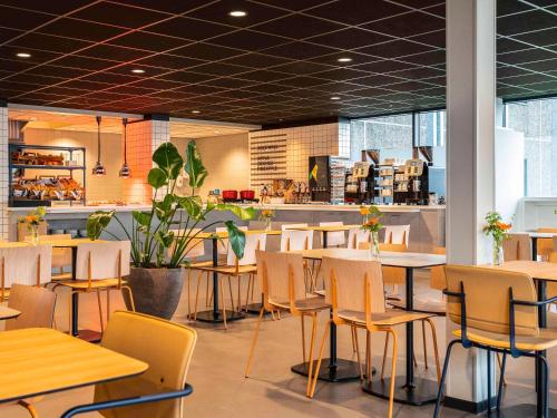 un restaurante con mesas y sillas en una cafetería en ibis budget Amsterdam Airport, en Badhoevedorp