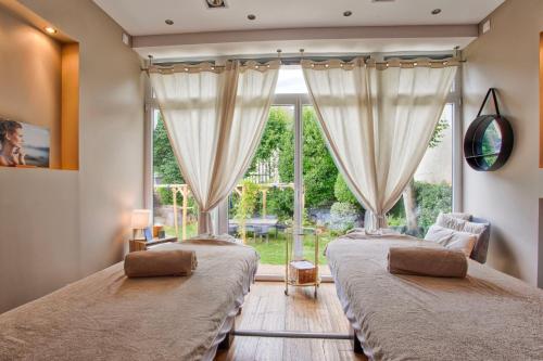 two beds in a room with a large window at Le Castel Cabourg hôtel & SPA- Restaurant La Calypso in Cabourg