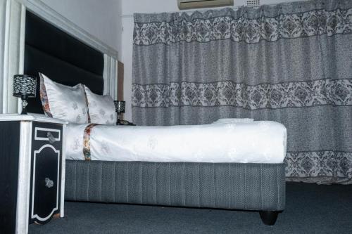 Cama en habitación con cortina y visor de falda en Beulah-land Hotel and Retreat Center en Mogoditshane
