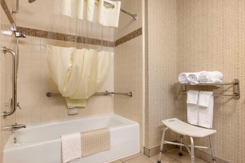 Best Western Los Angeles Worldport Hotel في ويلمنجتون: حمام مع حوض استحمام وكرسي ومناشف