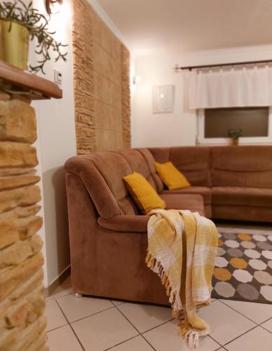 a living room with a brown couch and yellow pillows at Lexi Jakuzzis Apartman Balatonboglár in Balatonboglár