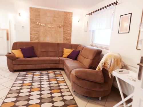 a living room with a brown couch and a rug at Lexi Jakuzzis Apartman Balatonboglár in Balatonboglár
