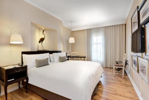 Cette chambre comprend un grand lit blanc et un bureau. dans l'établissement Protea Hotel by Marriott Mahikeng, à Mahikeng
