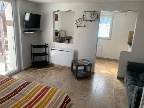 ein Wohnzimmer mit einem Bett und einem TV in der Unterkunft Appartement au calme et belle terrasse in Peyroules
