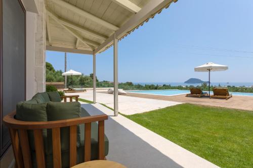 une terrasse couverte d'une maison avec un canapé et une piscine dans l'établissement Evylio Stone Houses, à Lithakia