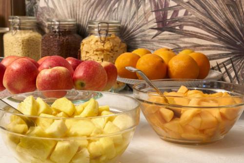 a table with bowls of apples and oranges and other fruits at Radisson Hotel Ferrara in Ferrara