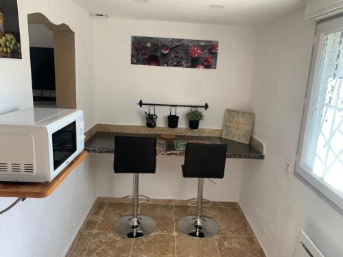 - une cuisine avec un four micro-ondes et deux tabourets de bar dans l'établissement Appartement au calme et belle terrasse, à Peyroules