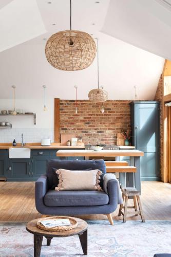 a living room with a blue couch and a kitchen at Badgers Cottage The Butler Collection in Fittleworth