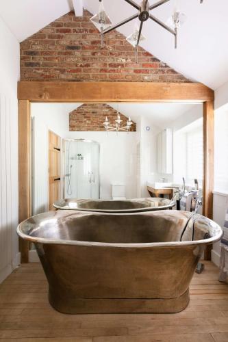 a large metal tub in a bathroom with a sink at Badgers Cottage The Butler Collection in Fittleworth