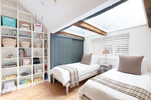 a bedroom with two beds and a book shelf at Badgers Cottage in Fittleworth