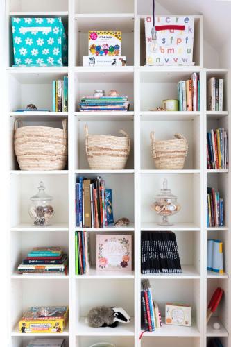 a white book shelf filled with books and baskets at Badgers Cottage The Butler Collection in Fittleworth