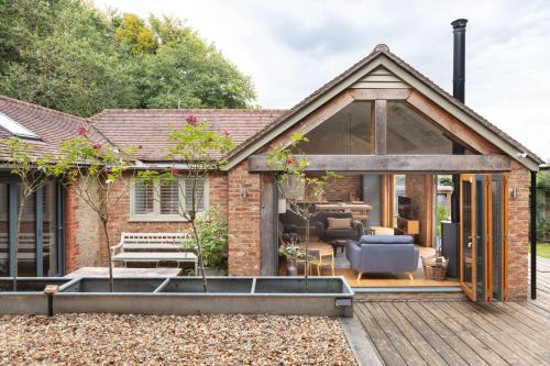 an extension to a brick house with a deck at Badgers Cottage The Butler Collection in Fittleworth